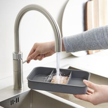 Ninka ECO-top Lid with Odour Filter being used to rinse food waste in a kitchen sink  showing the stainless steel design and odour filter functionality in action
